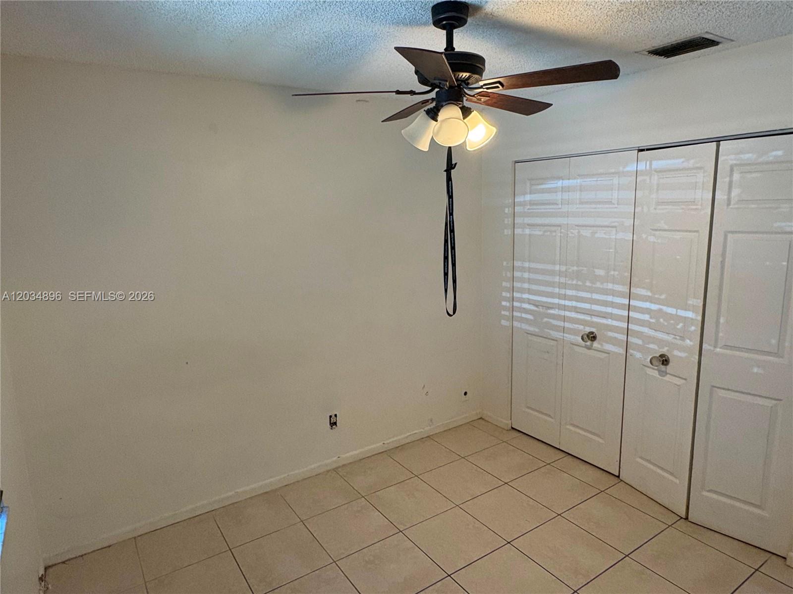 A room with white walls, tiled flooring, a ceiling fan, and white closet doors — 3819 SW 69th Ave # L, Miramar FL 33023, MIRAMAR, FL