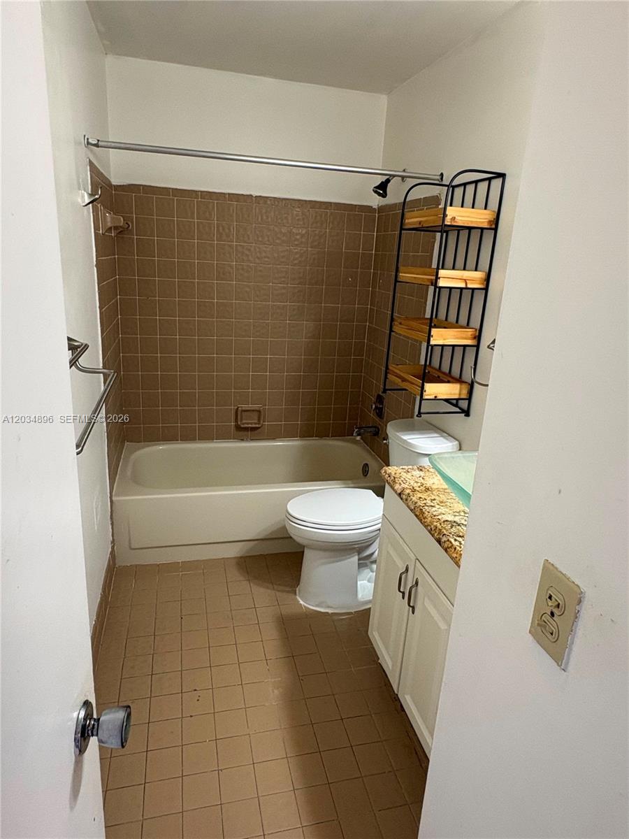 This bathroom features a bathtub with brown wall tiles, a toilet, and a vanity — 3819 SW 69th Ave # L, Miramar FL 33023, MIRAMAR, FL