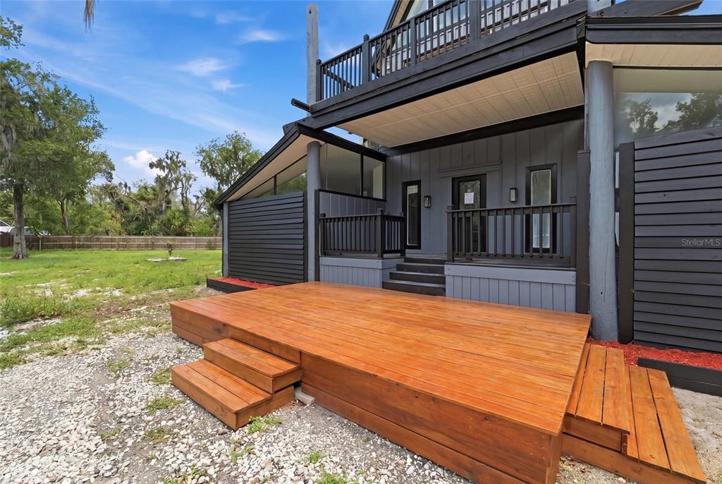 A wooden deck with steps leads to a gray house with a black railing — 7210 VALRIE LANE, RIVERVIEW, FL