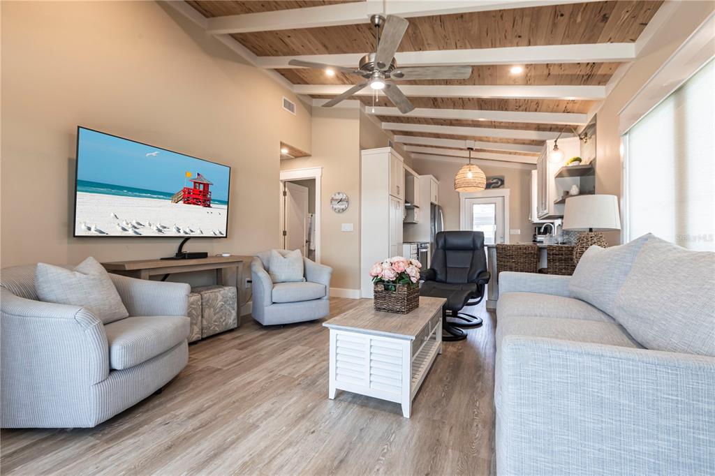 A living room features light wood flooring, a vaulted ceiling with beams, and neutral furniture — 6020 MIDNIGHT PASS ROAD UNIT 39, SARASOTA, FL