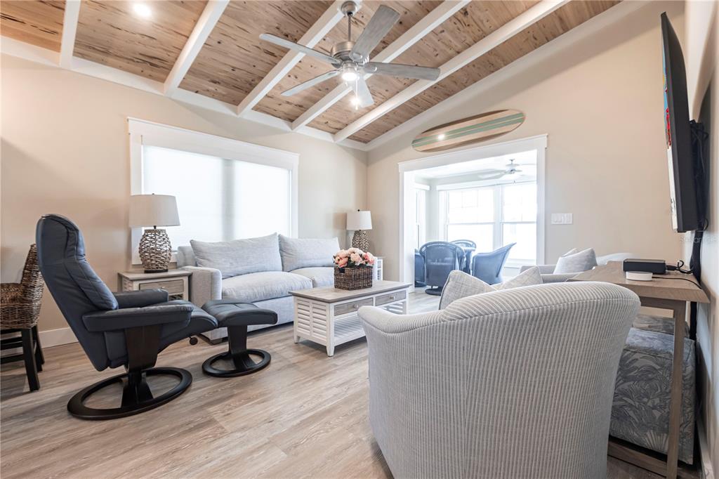 A living room features a vaulted wood-paneled ceiling, a ceiling fan, and coastal-style furniture — 6020 MIDNIGHT PASS ROAD UNIT 39, SARASOTA, FL