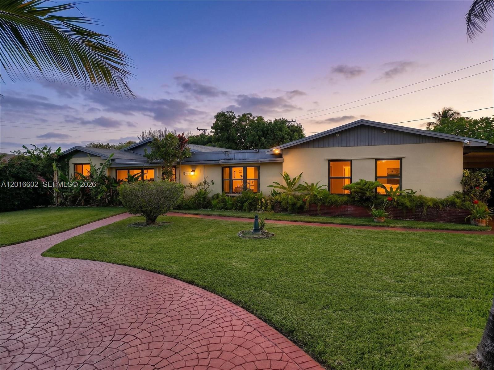 A single-story house with a red patterned driveway and a green lawn at dusk — 10900 SW 177th Ter, Miami FL 33157, MIAMI, FL
