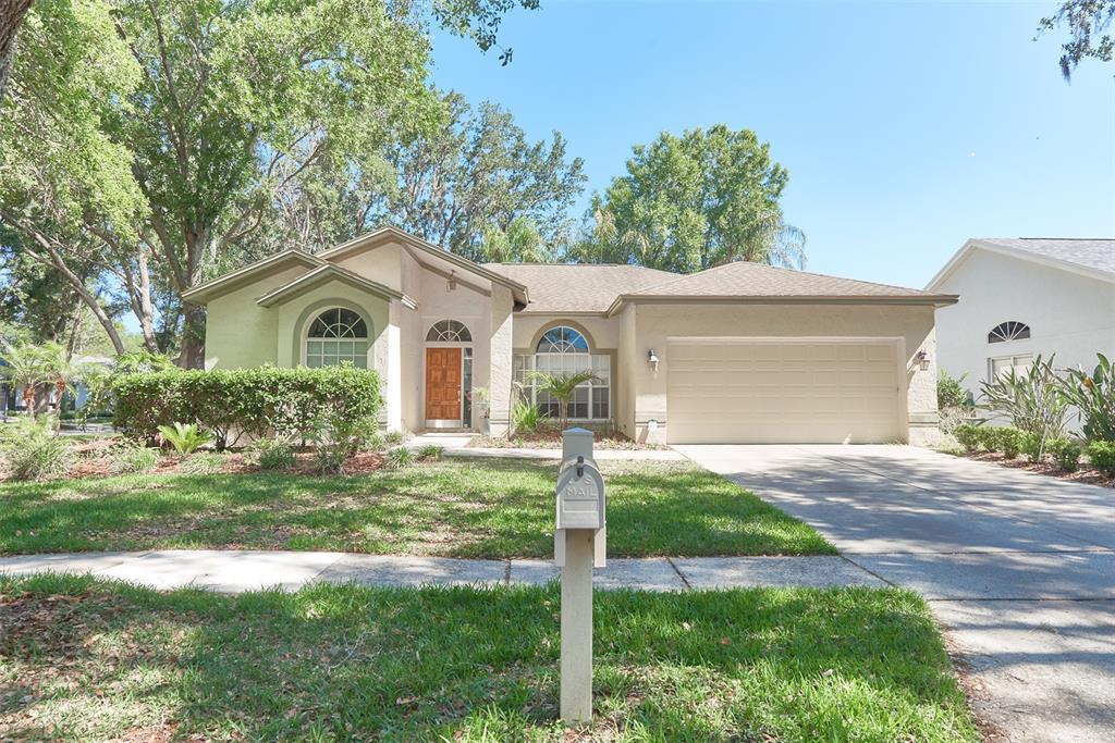 A single-story house with a beige stucco exterior, a two-car garage, and a front lawn — 9302 HERITAGE OAK COURT, TAMPA, FL