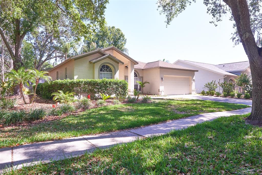 A single-story house with a beige stucco exterior, a two-car garage, and a landscaped yard — 9302 HERITAGE OAK COURT, TAMPA, FL