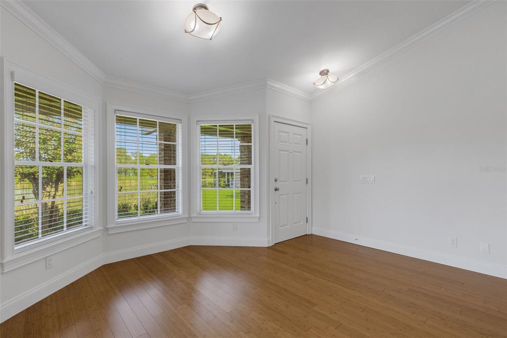 An empty room with white walls, wood flooring, large windows, and two ceiling lights — 1154 WATERFALL LANE UNIT n/a, LAKELAND, FL