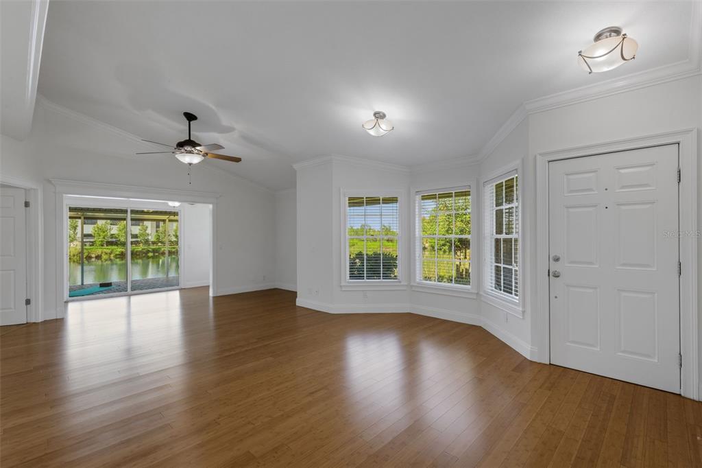 An empty living room features hardwood floors, a ceiling fan, and a view of water — 1154 WATERFALL LANE UNIT n/a, LAKELAND, FL