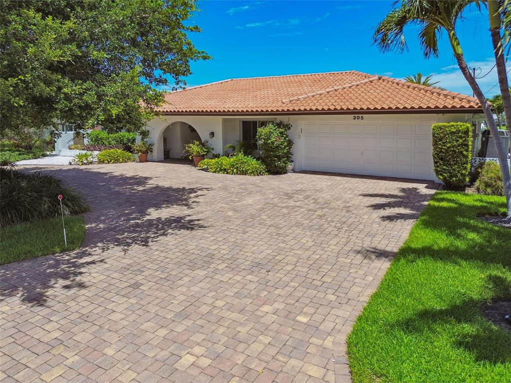A single-story house with a tiled roof, white exterior, and a large brick paver driveway — 205 HARRISON AVENUE, BELLEAIR BEACH, FL