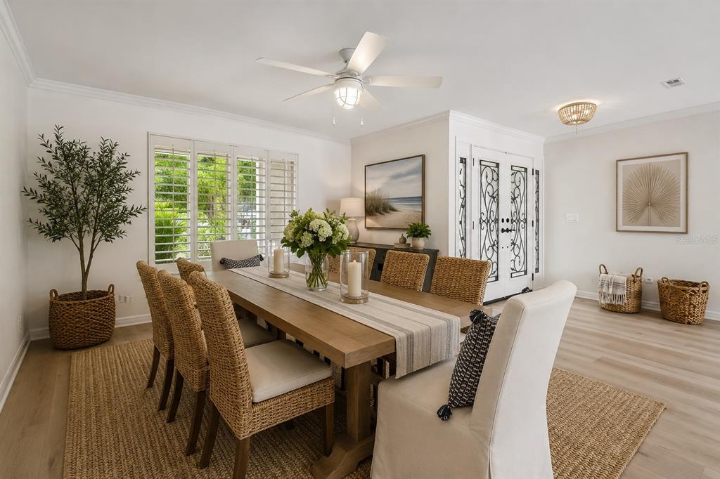 A dining room features a wooden table, woven chairs, a ceiling fan, and plantation shutters — 205 HARRISON AVENUE, BELLEAIR BEACH, FL