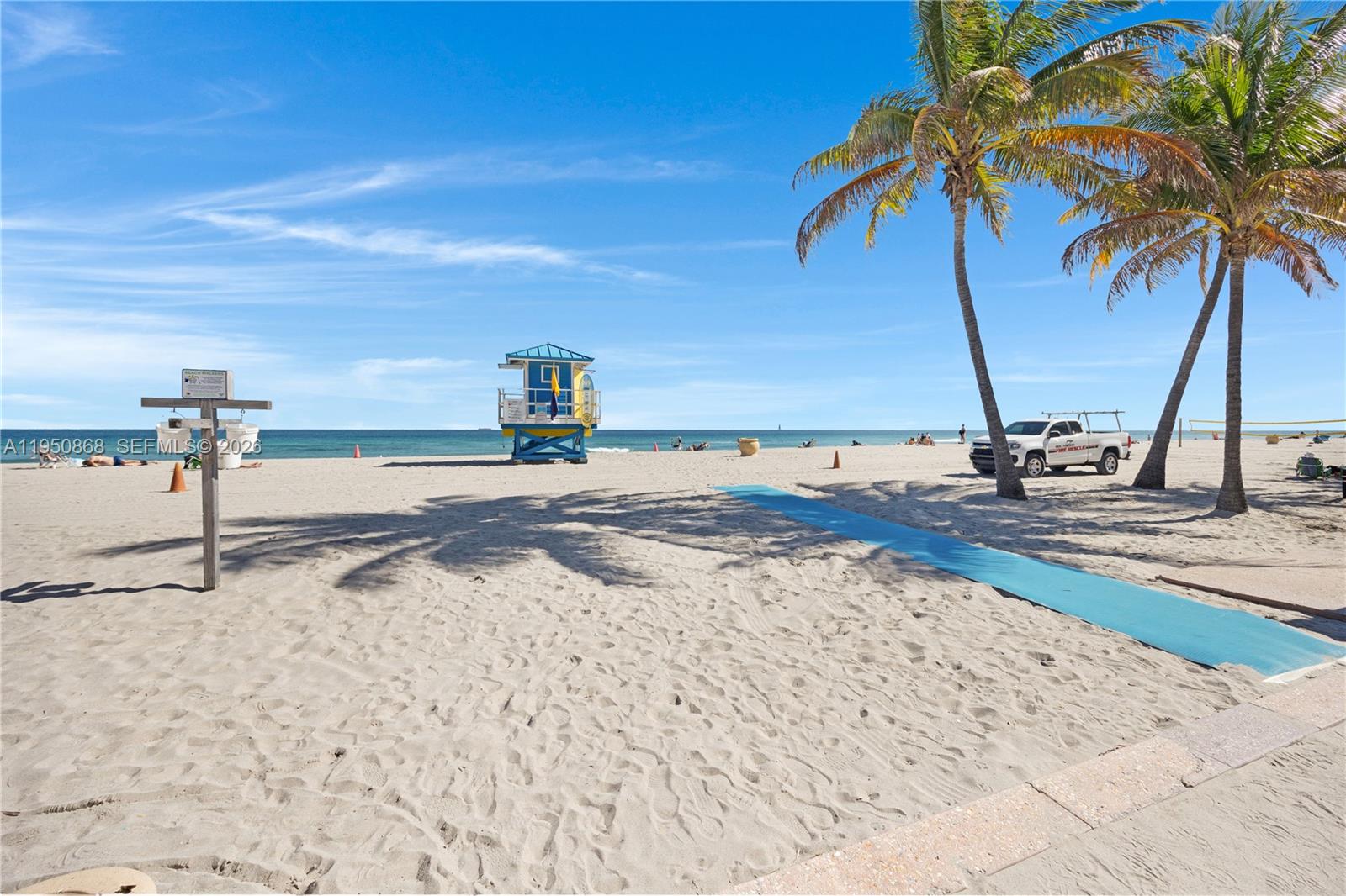 A sandy beach features a blue lifeguard tower, palm trees, and a white pickup truck — 320 New York St, Hollywood FL 33019, HOLLYWOOD, FL