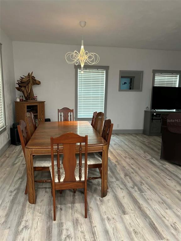 A dining area features a wooden table, six chairs, a modern light fixture, and wood-look flooring — 2028 OLD NEW YORK AVENUE, DELAND, FL