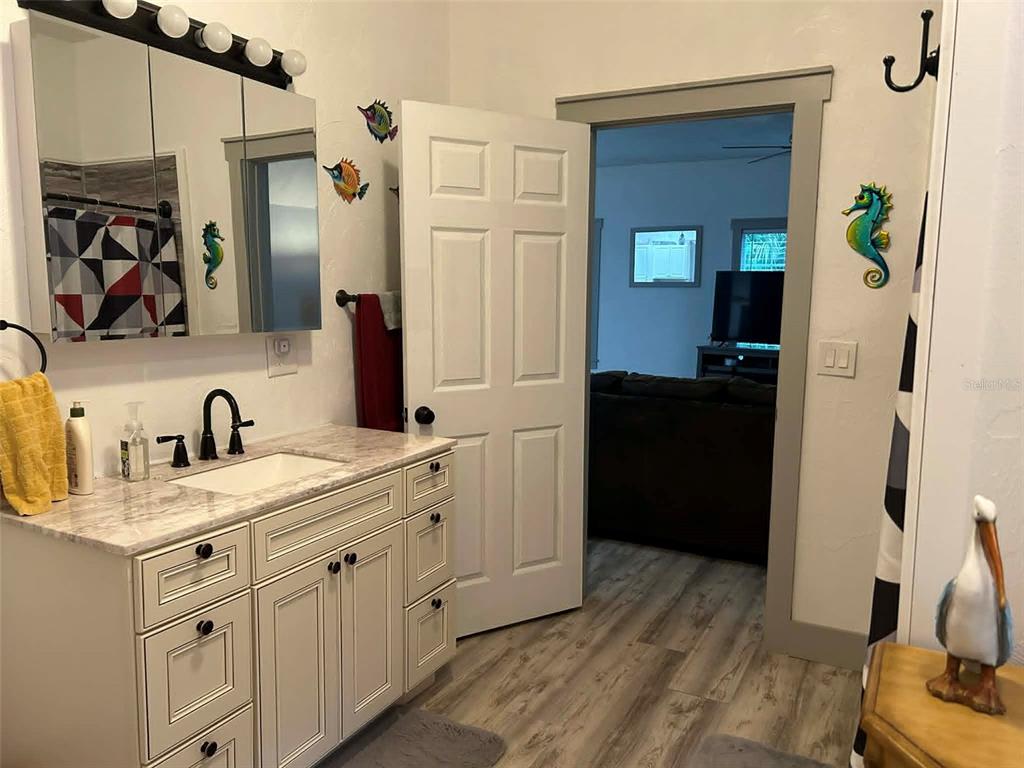 A bathroom features a white vanity, a mirrored medicine cabinet, and coastal-themed wall decor — 2028 OLD NEW YORK AVENUE, DELAND, FL