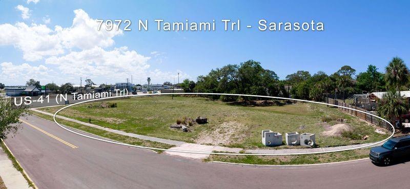 An aerial view shows a vacant, grassy lot bordered by a road and trees — 7972 N TAMIAMI TRAIL, SARASOTA, FL