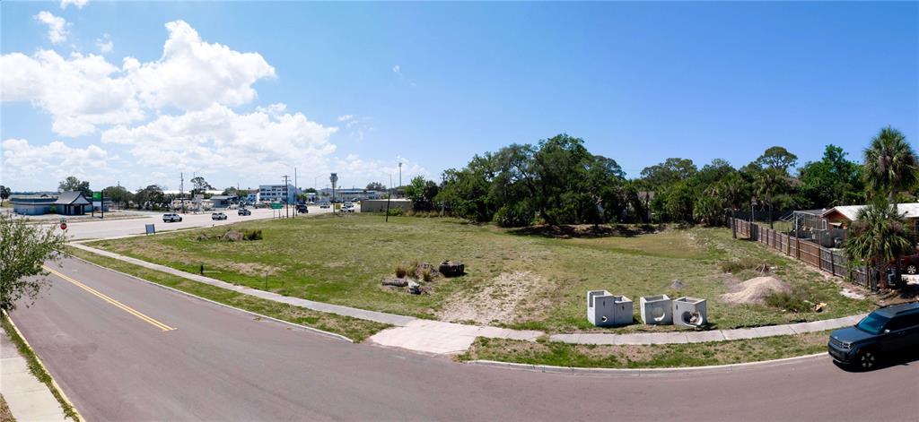 A vacant, grassy corner lot sits adjacent to a paved road with concrete drainage structures — 7972 N TAMIAMI TRAIL, SARASOTA, FL