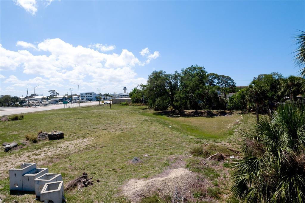 An elevated view of a vacant, grassy lot with trees and a distant road — 7972 N TAMIAMI TRAIL, SARASOTA, FL