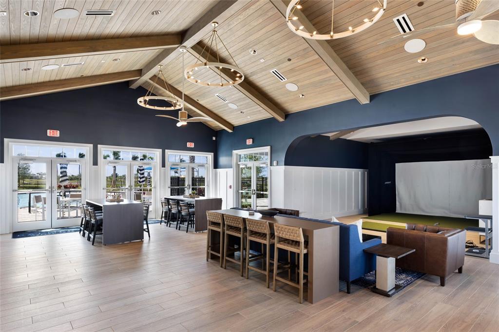 A spacious room features a vaulted wood ceiling, dark blue walls, and a golf simulator — 17698 SYLVESTER DRIVE, VENICE, FL