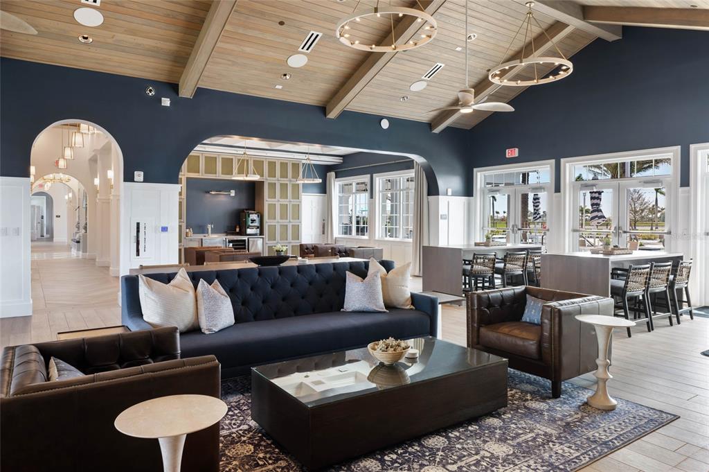 A spacious lounge features a dark blue sofa, leather armchairs, wood-paneled ceilings, and arched doorways — 17698 SYLVESTER DRIVE, VENICE, FL