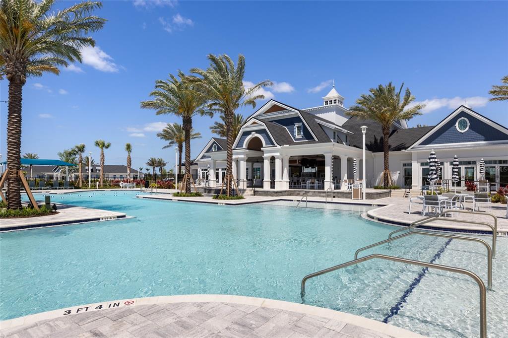 A swimming pool sits in front of a large clubhouse building with palm trees — 17698 SYLVESTER DRIVE, VENICE, FL