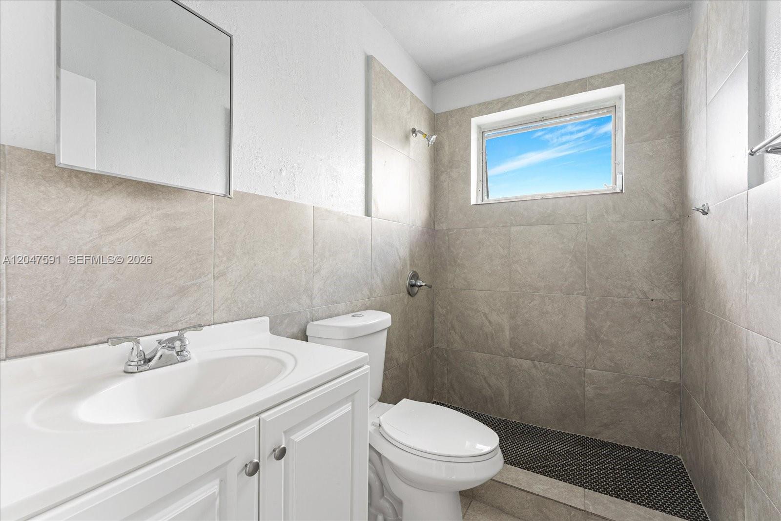 A bathroom features a white vanity, a toilet, and a tiled shower area with a window — 3255 W Flagler St # 2, Miami FL 33135, MIAMI, FL
