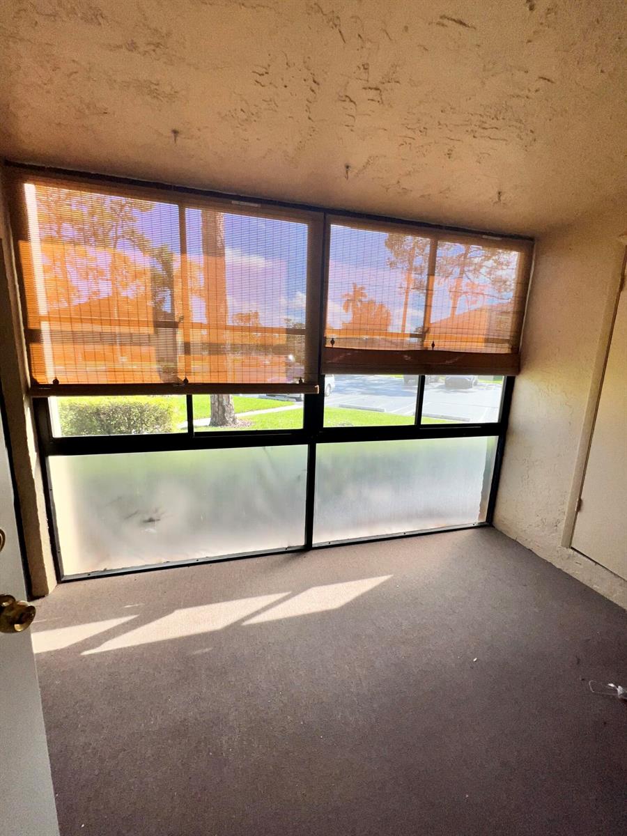 A sunroom with carpeted flooring, large windows with bamboo shades, and frosted lower glass panels — 231 Pine Hov Circle # 1, FL 33463, FL