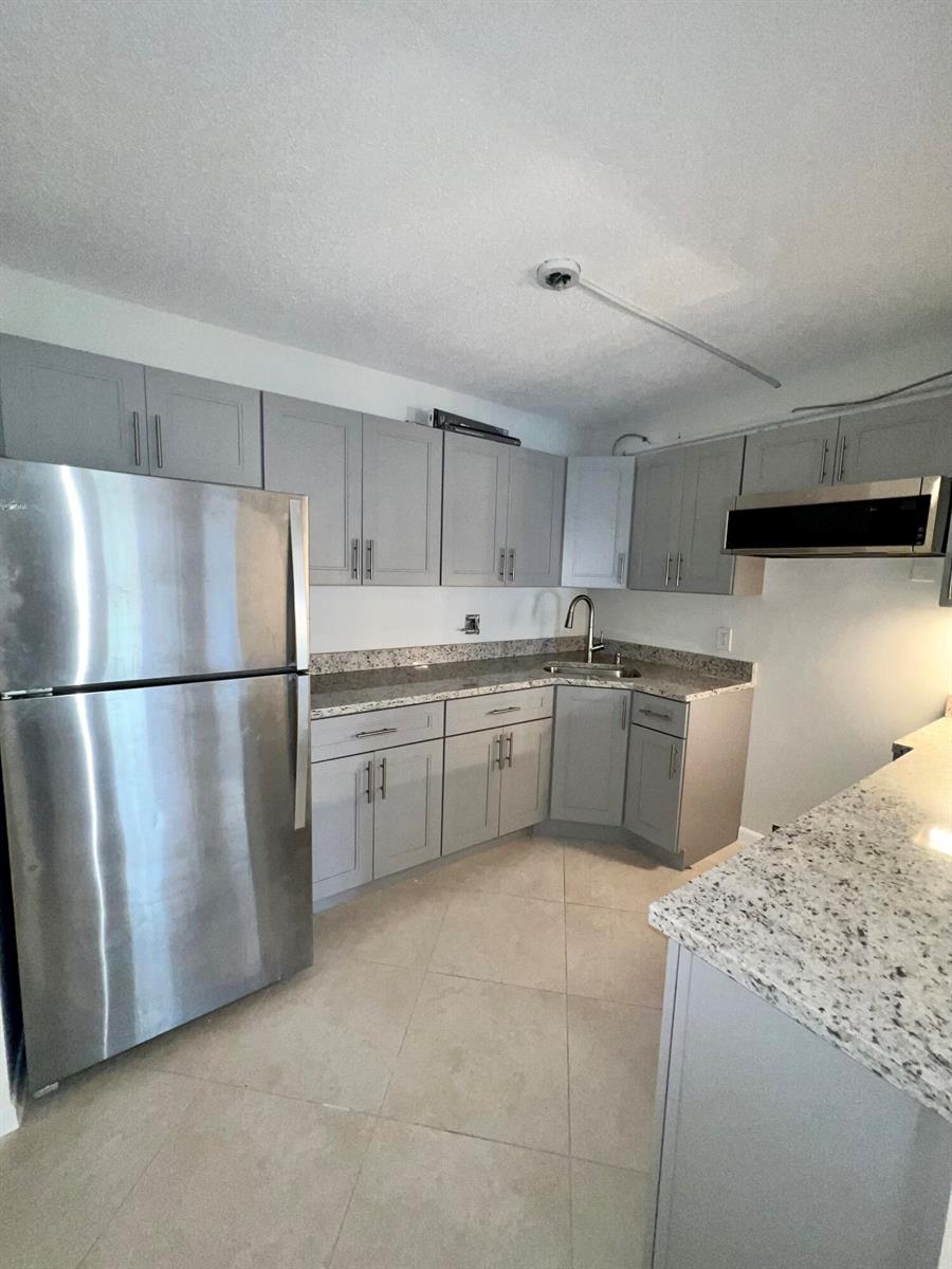 A kitchen features gray cabinets, stainless steel appliances, and speckled granite countertops — 231 Pine Hov Circle # 1, FL 33463, FL