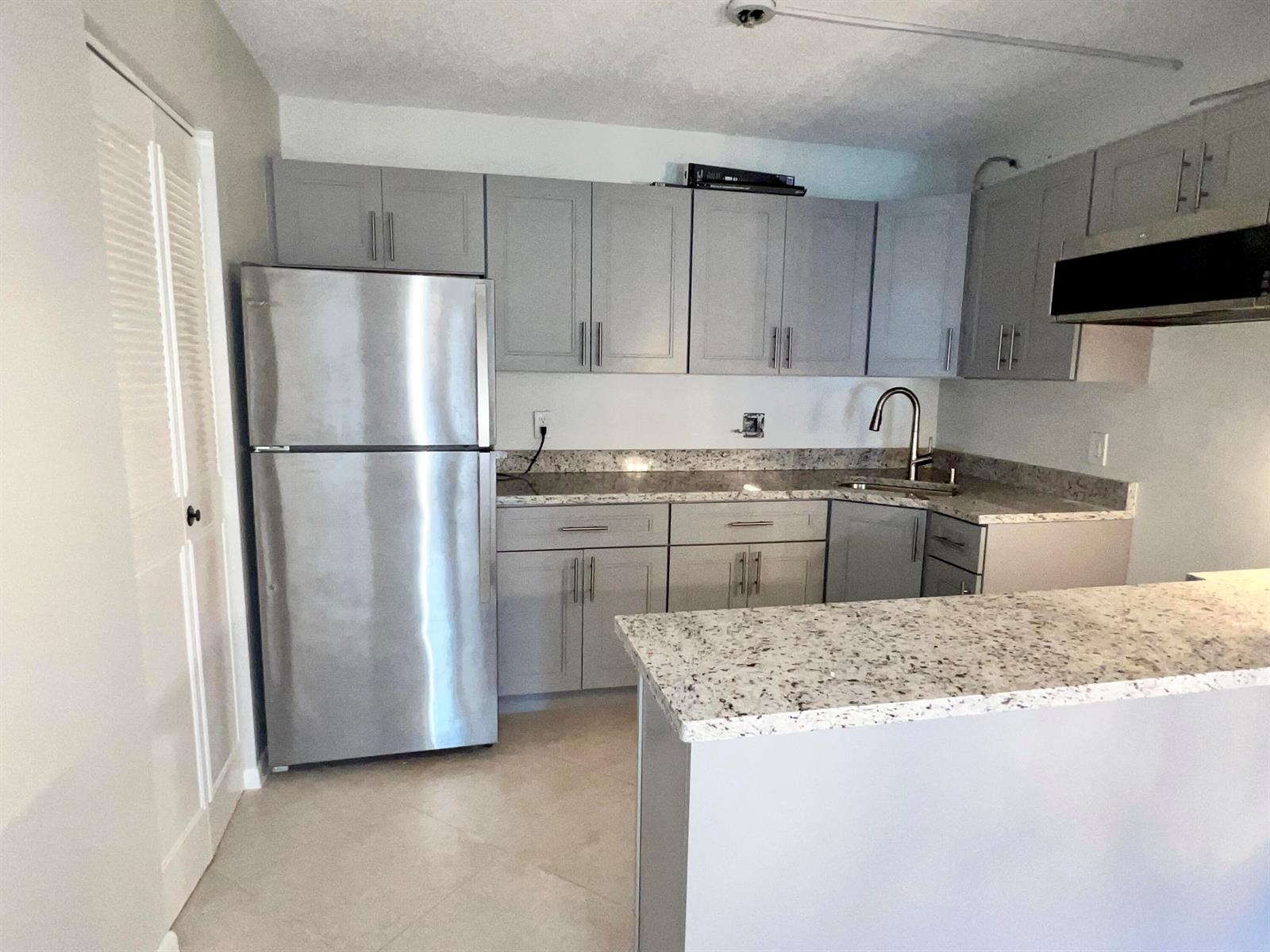 A kitchen features gray cabinets, stainless steel appliances, and speckled granite countertops — 231 Pine Hov Circle # 1, FL 33463, FL