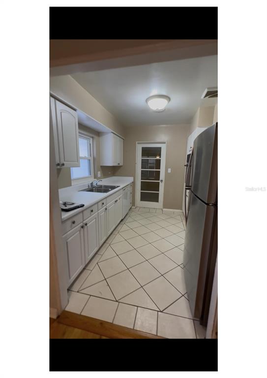 A galley kitchen features white cabinets, stainless steel appliances, and light-colored diagonal floor tiles — 2014 LINDA STREET, ORLANDO, FL