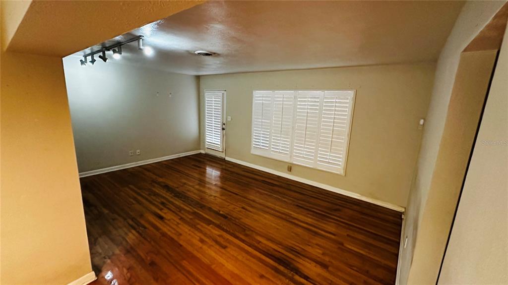 An empty room features hardwood floors, white plantation shutters, and a ceiling track lighting fixture — 2014 LINDA STREET, ORLANDO, FL