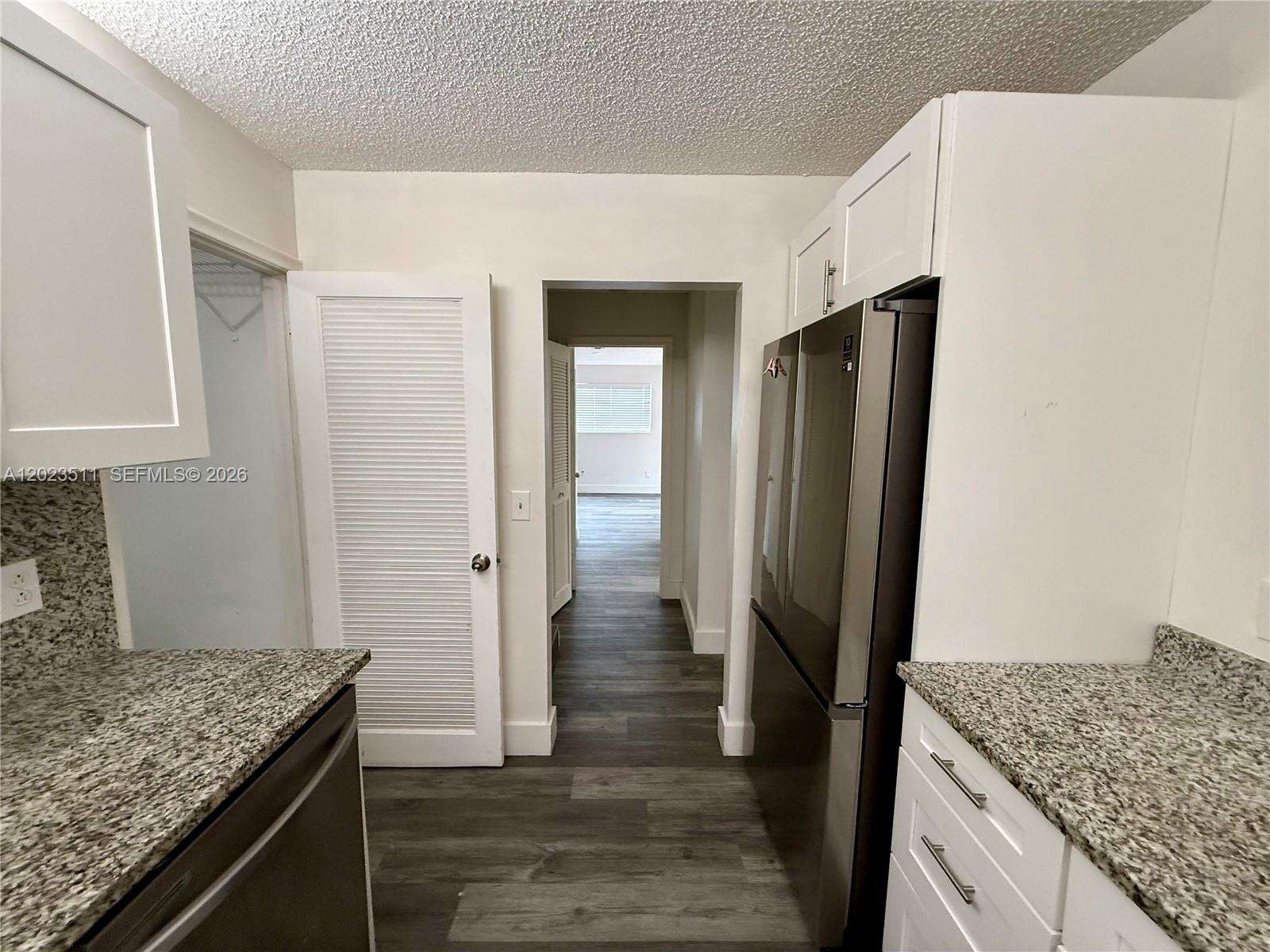 A kitchen features white cabinets, granite countertops, stainless steel appliances, and wood-look flooring — 4300 S Landar Dr, Lake Worth FL 33463, LAKE WORTH, FL
