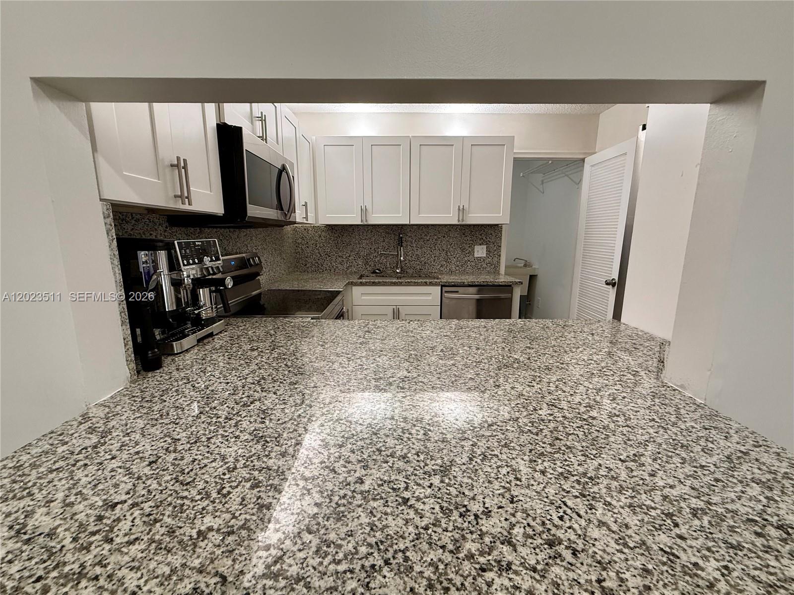 A kitchen features white cabinets, granite countertops, and stainless steel appliances — 4300 S Landar Dr, Lake Worth FL 33463, LAKE WORTH, FL