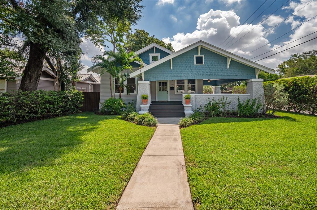 A blue bungalow-style house features a front porch, a concrete walkway, and a grassy lawn — 5301 N CENTRAL AVENUE, TAMPA, FL