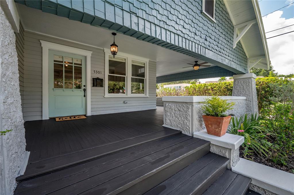 A covered front porch features dark wooden steps, a light blue door, and shingled siding — 5301 N CENTRAL AVENUE, TAMPA, FL