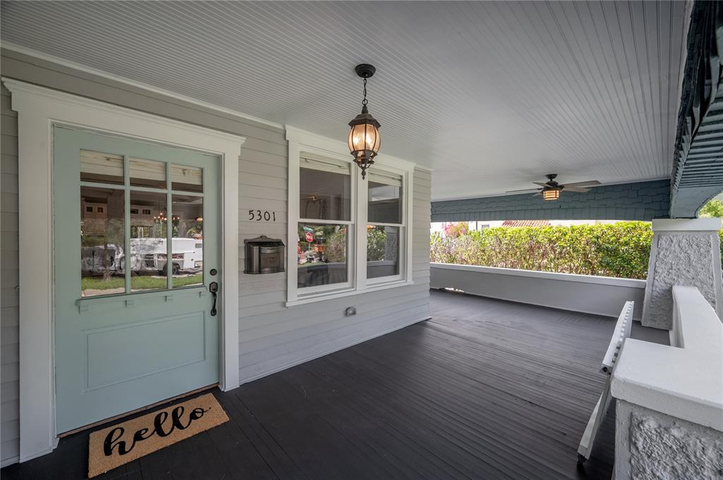 A covered front porch features a light blue door, dark wood flooring, and a ceiling fan — 5301 N CENTRAL AVENUE, TAMPA, FL
