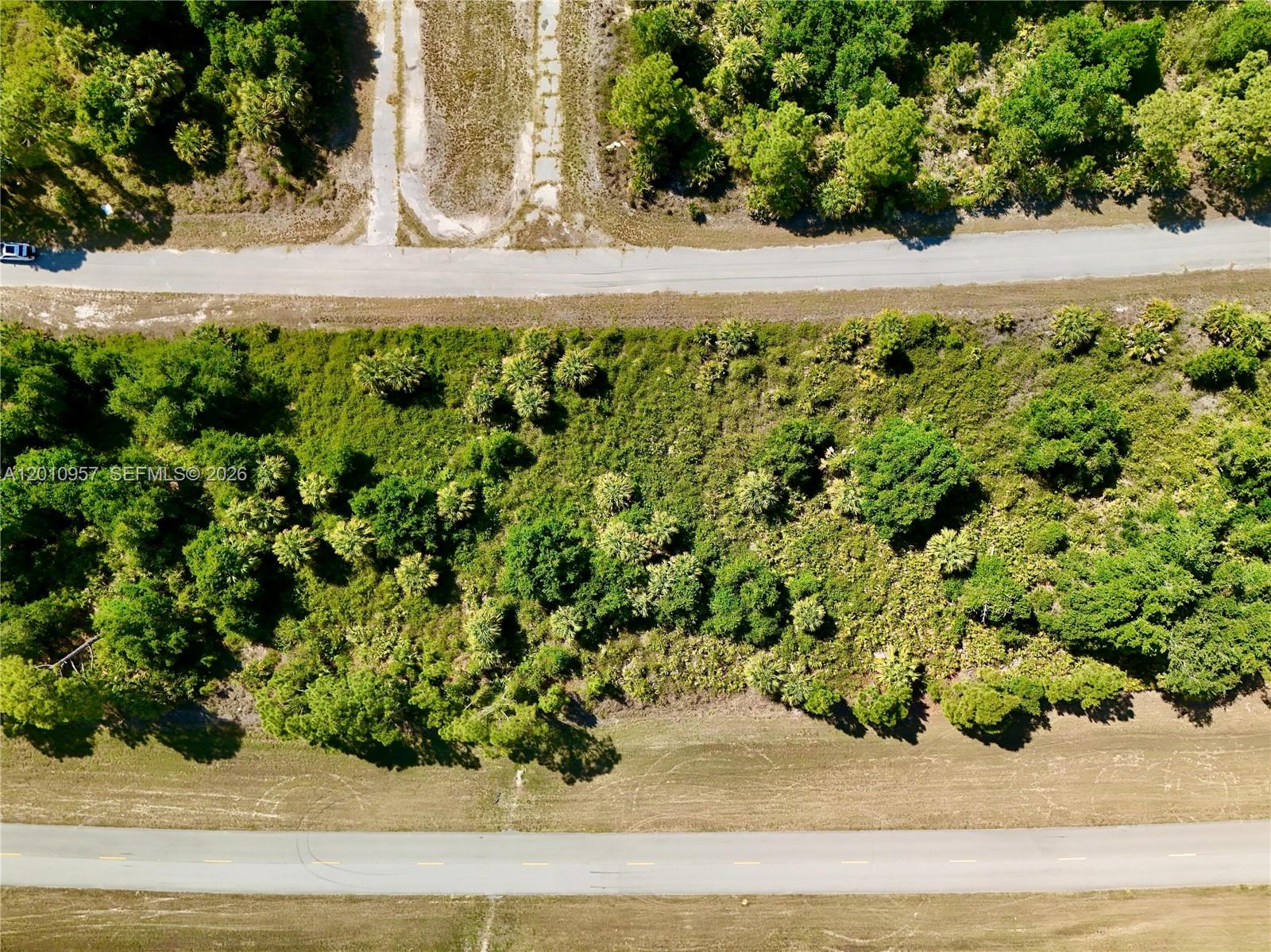 An aerial view shows a wooded lot situated between two paved roads — 0 CUSTER CIR, North Port FL 34288, NORTH PORT, FL
