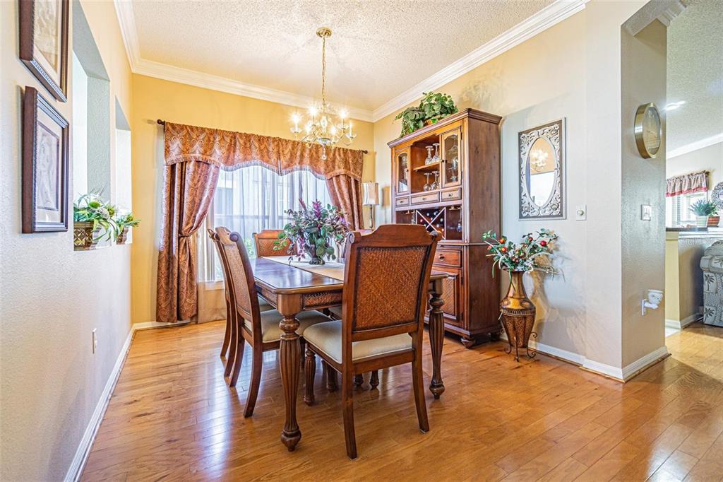 A dining room features a wooden table, matching chairs, a hutch, and hardwood flooring — 2514 SANDY HILL COURT, HOLIDAY, FL