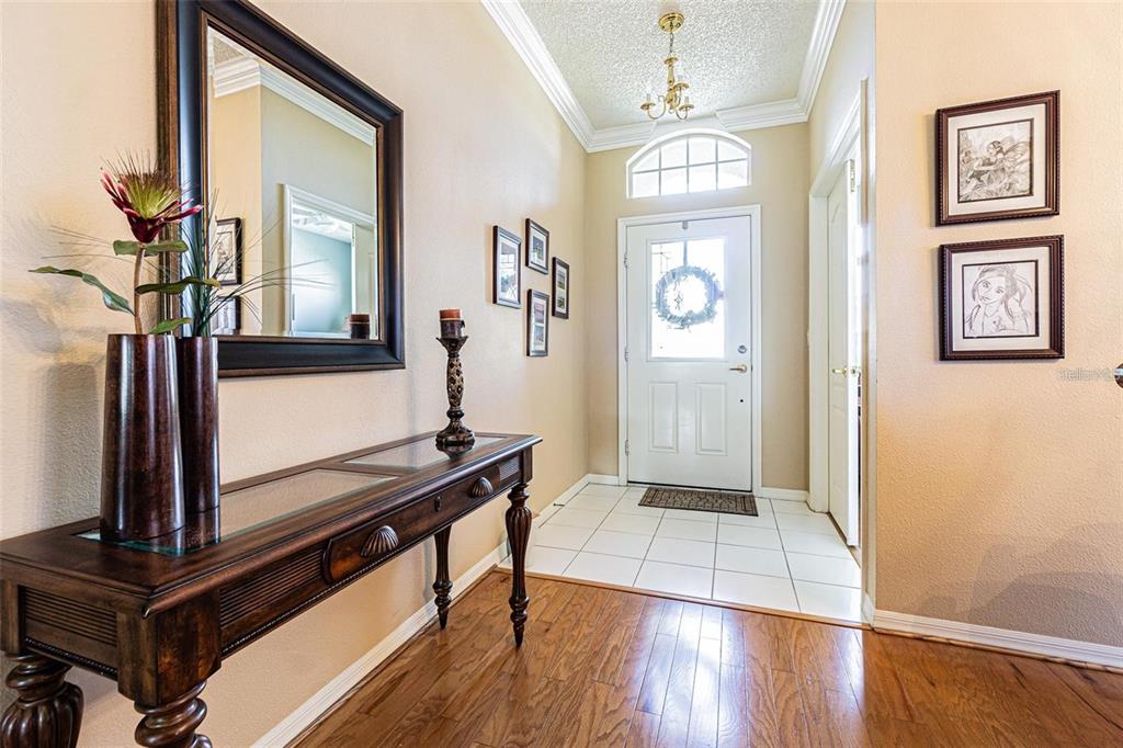 A foyer features a wood console table, a large mirror, and a white front door — 2514 SANDY HILL COURT, HOLIDAY, FL