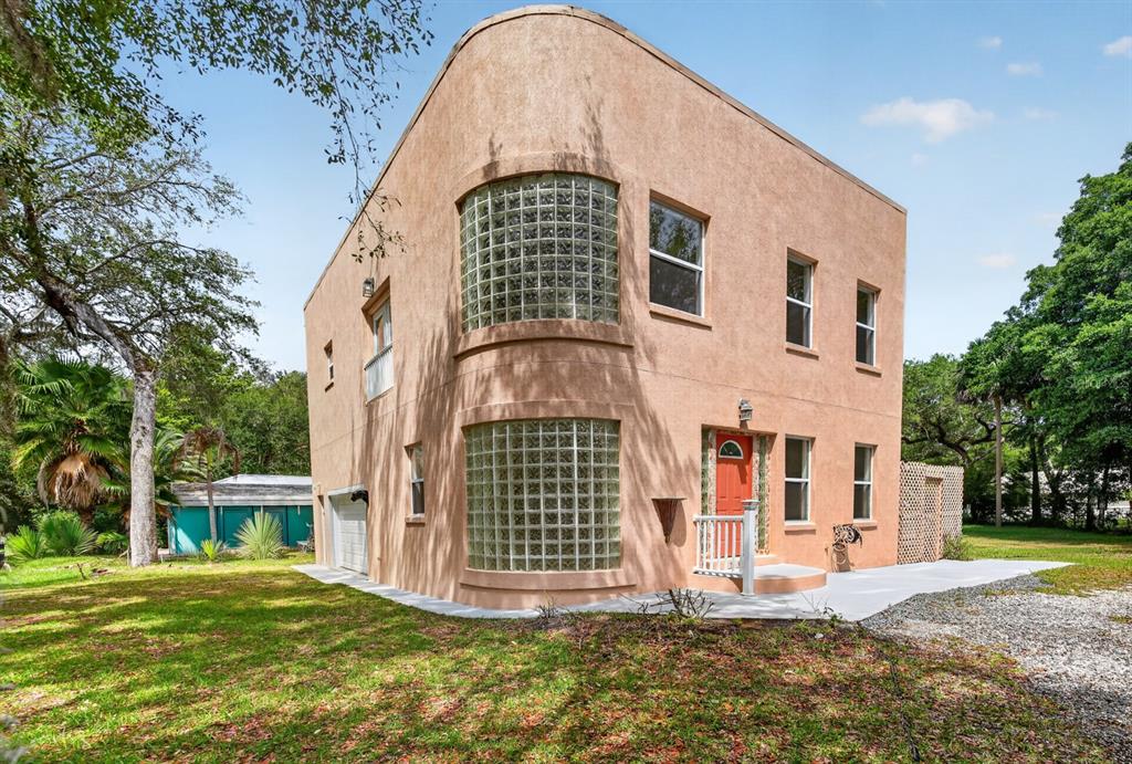 A two-story stucco house features curved glass block windows and a bright red front door — 5300 N OCEAN SHORE BOULEVARD, PALM COAST, FL
