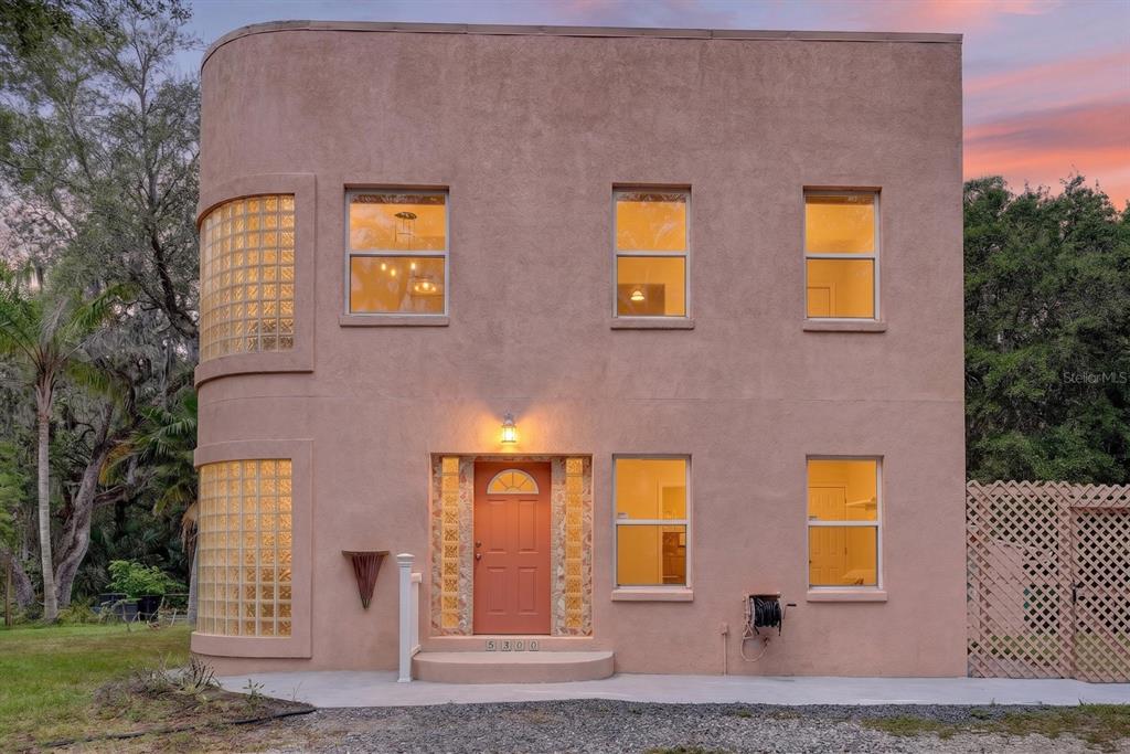 A two-story stucco house with a curved glass block corner and an orange front door — 5300 N OCEAN SHORE BOULEVARD, PALM COAST, FL