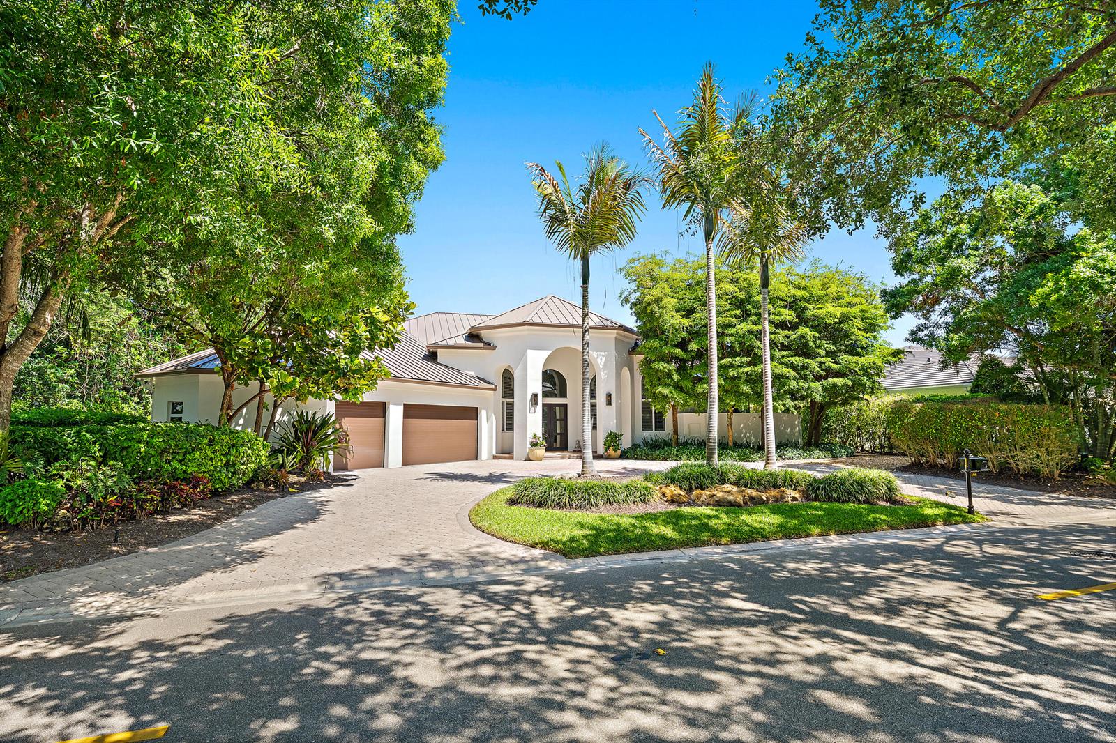 A white single-story house with a metal roof, two-car garage, and palm trees in front — 106 Commodore Drive, Jupiter FL 33477, JUPITER, FL