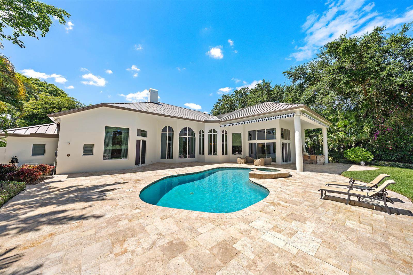 A white house with a metal roof overlooks a swimming pool and stone patio — 106 Commodore Drive, Jupiter FL 33477, JUPITER, FL