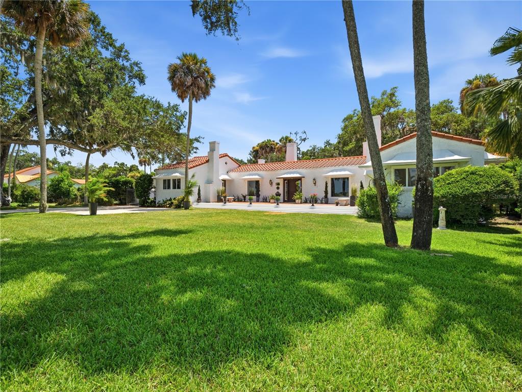 A single-story white house with a red tile roof sits behind a large green lawn — 636 N RIVERSIDE DRIVE, NEW SMYRNA BEACH, FL