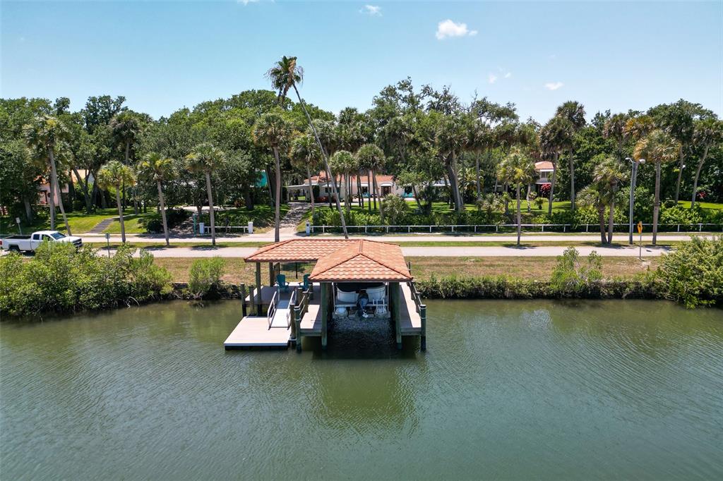 An aerial view shows a boat dock with a tiled roof on a calm waterway — 636 N RIVERSIDE DRIVE, NEW SMYRNA BEACH, FL