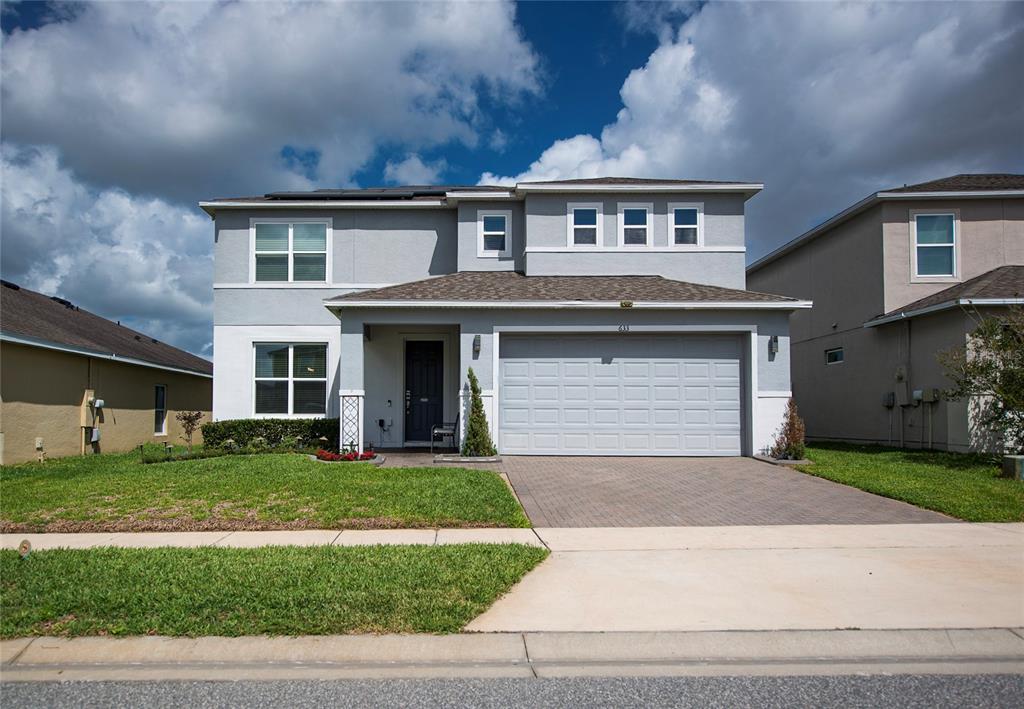A two-story suburban house with a gray exterior, a two-car garage, and a paved driveway — 633 OGELTHORPE DRIVE, DAVENPORT, FL