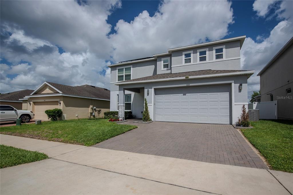 A two-story gray house with a paved driveway and a two-car garage — 633 OGELTHORPE DRIVE, DAVENPORT, FL