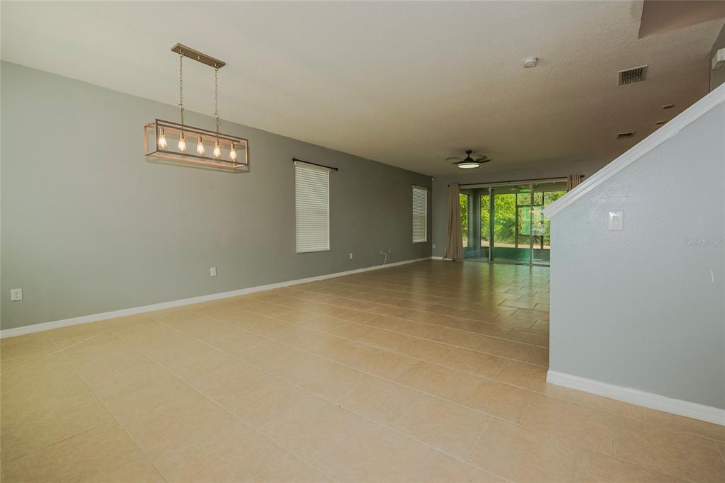 An open-concept living and dining area features light tile flooring and a modern rectangular chandelier — 633 OGELTHORPE DRIVE, DAVENPORT, FL