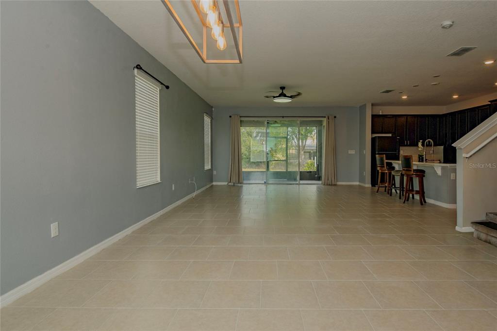 An open-concept living area features light tile flooring, gray walls, and a kitchen with stools — 633 OGELTHORPE DRIVE, DAVENPORT, FL