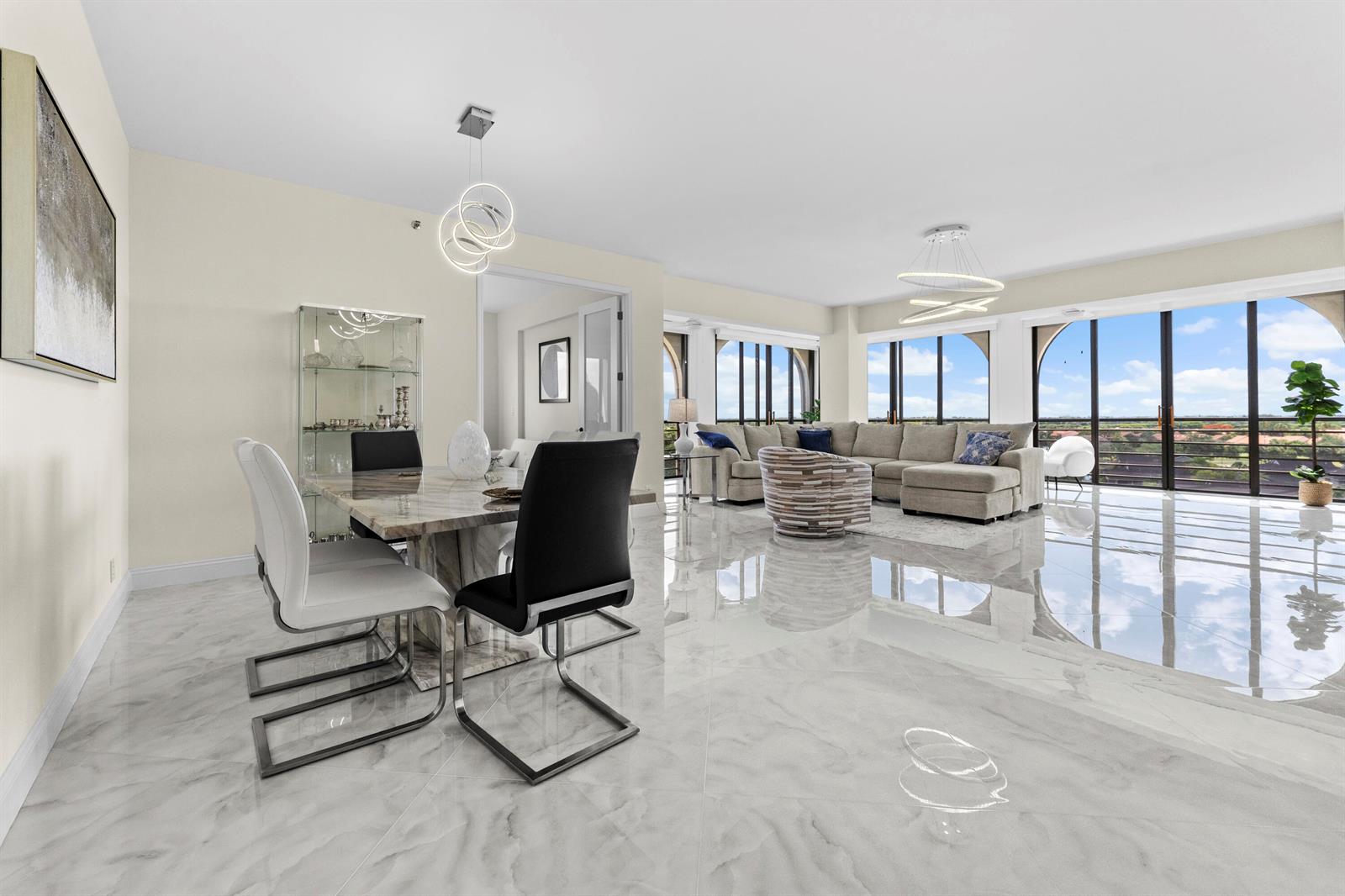 An open-concept living and dining area features marble-look tile floors and floor-to-ceiling windows — 7578 Regency Lake Drive # 802, Boca Raton FL 33433, BOCA RATON, FL