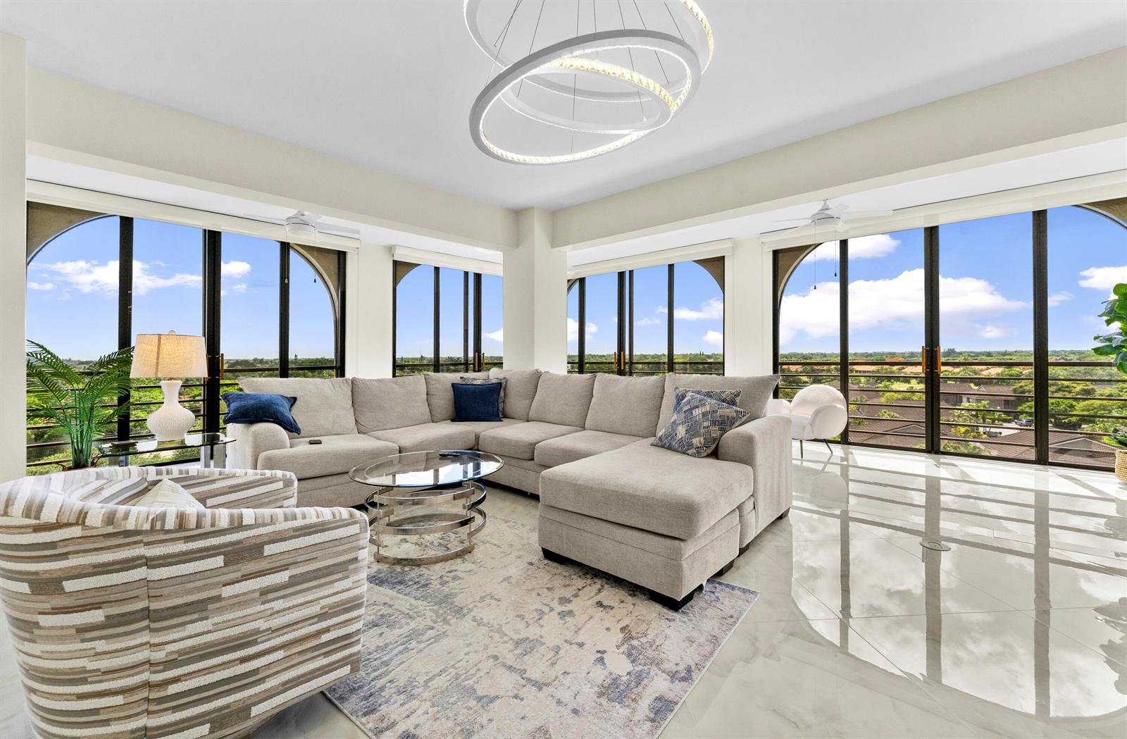 A living room features a sectional sofa, glass coffee table, and floor-to-ceiling windows with views — 7578 Regency Lake Drive # 802, Boca Raton FL 33433, BOCA RATON, FL