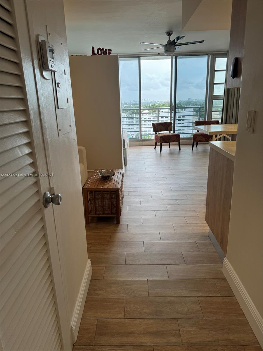 A view from a doorway shows a living area with wood-look tile flooring and balcony access — 1720 Harrison St # 15F, Hollywood FL 33020, HOLLYWOOD, FL