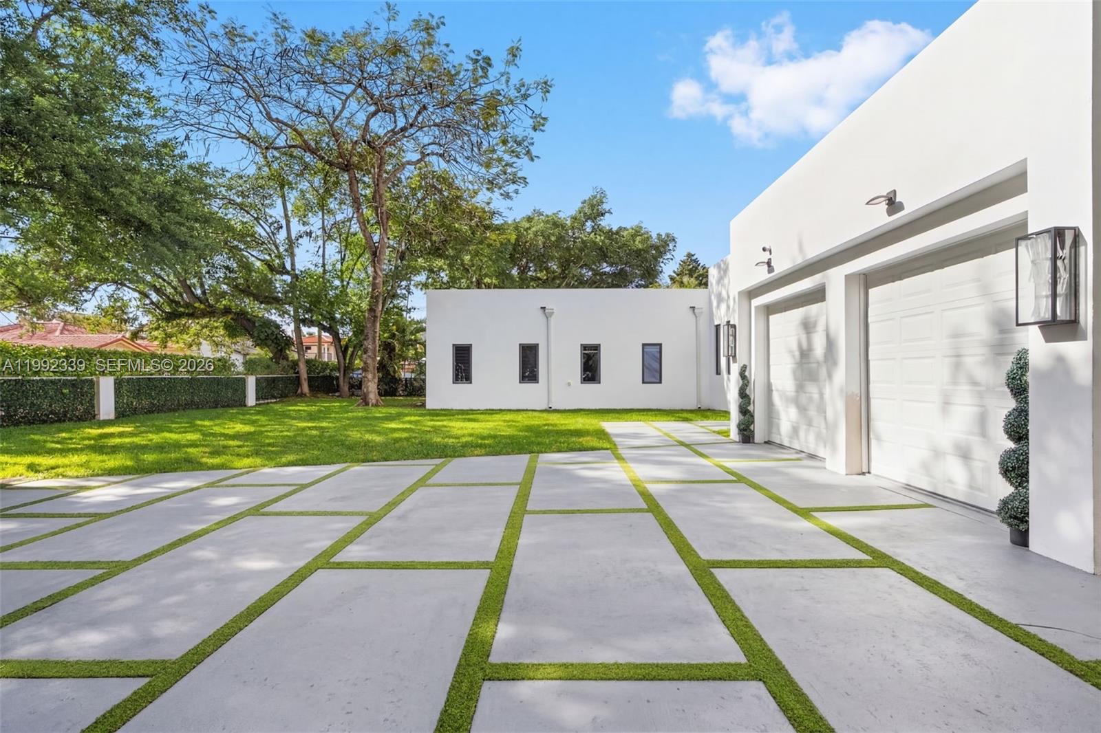 A modern white house features a large driveway with concrete pavers and green grass strips — 1120 Wallace St, Coral Gables FL 33134, CORAL GABLES, FL