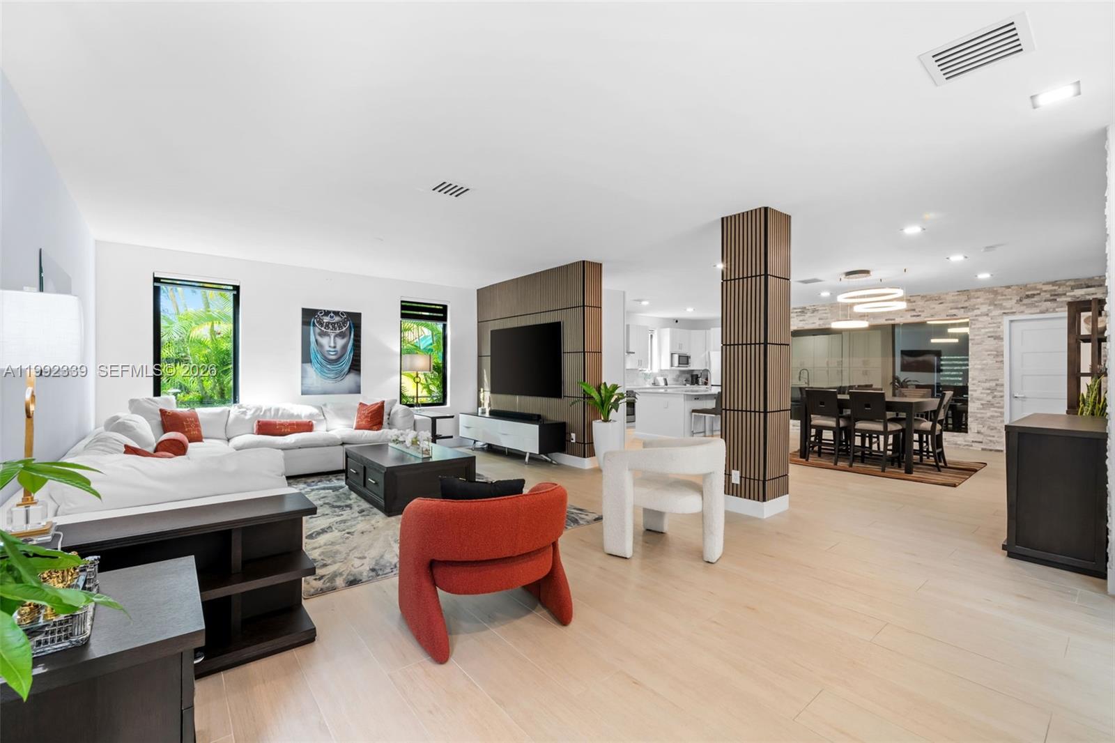 An open-concept living and dining area features light wood floors and wood-slat accent columns — 1120 Wallace St, Coral Gables FL 33134, CORAL GABLES, FL